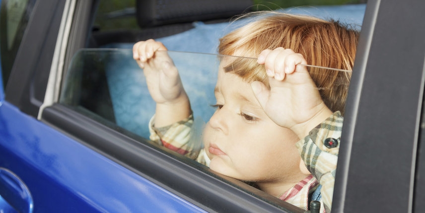 Young child looking out car window during hot weather
