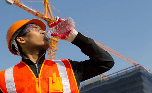 A construction worker drinks water during work to stay hydrated.