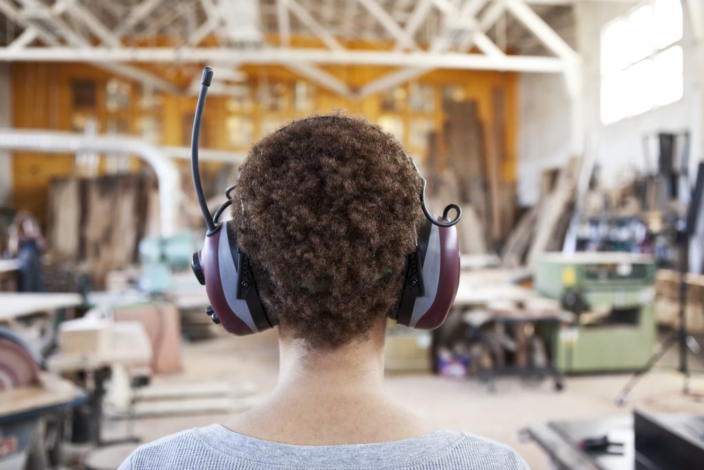 Woman Factory Worker Wearing Hearing Protection in a Woodworking Factory