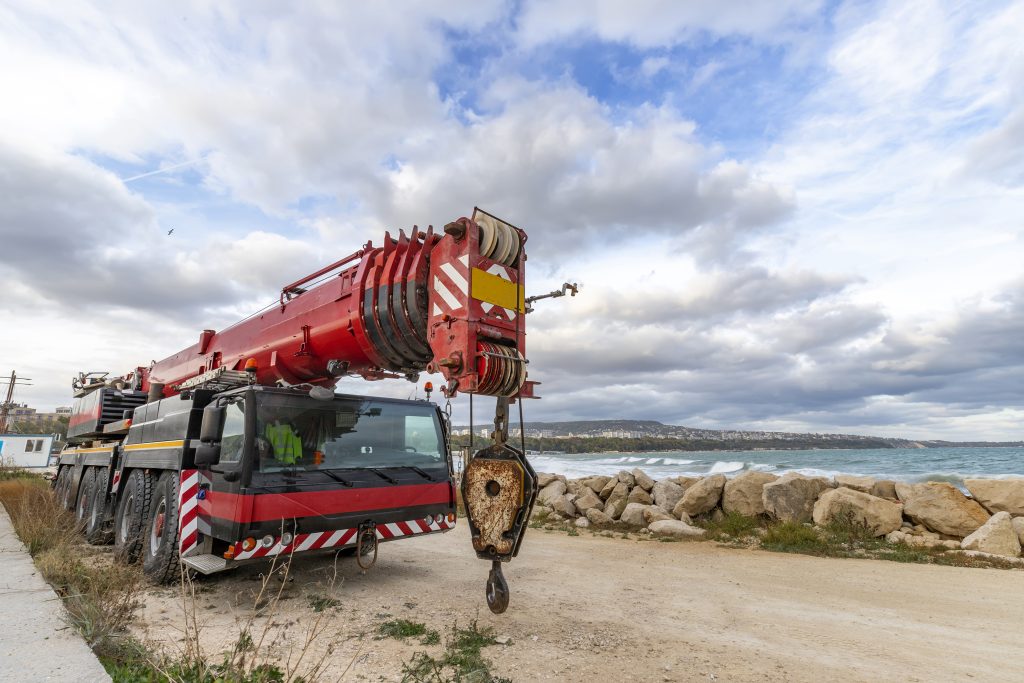 Heavy-duty mobile crane beside a rocky shore